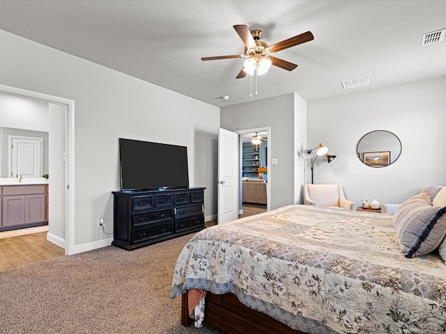 bedroom with light colored carpet, visible vents, connected bathroom, and baseboards