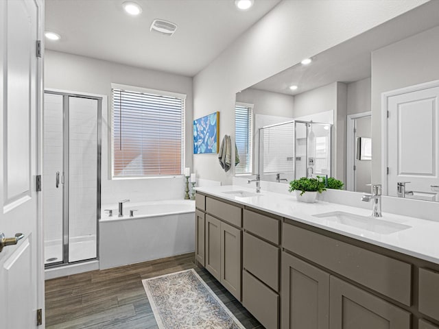 bathroom with wood finished floors, a stall shower, a sink, and a bath