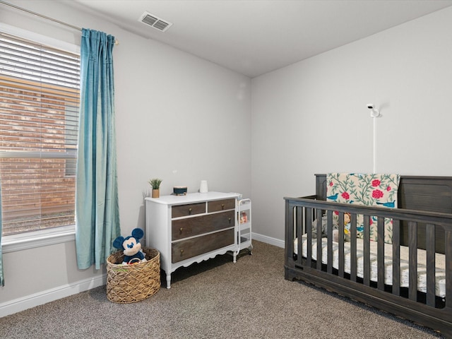 carpeted bedroom with visible vents, a crib, and baseboards