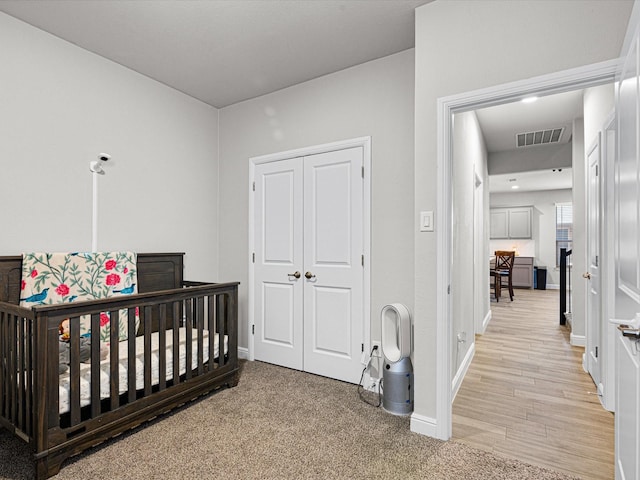 bedroom featuring a nursery area, a closet, visible vents, and baseboards