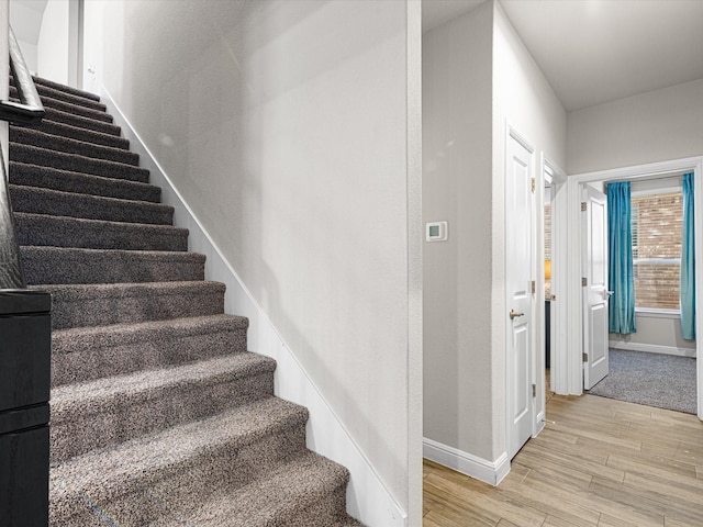 staircase featuring baseboards and wood finished floors