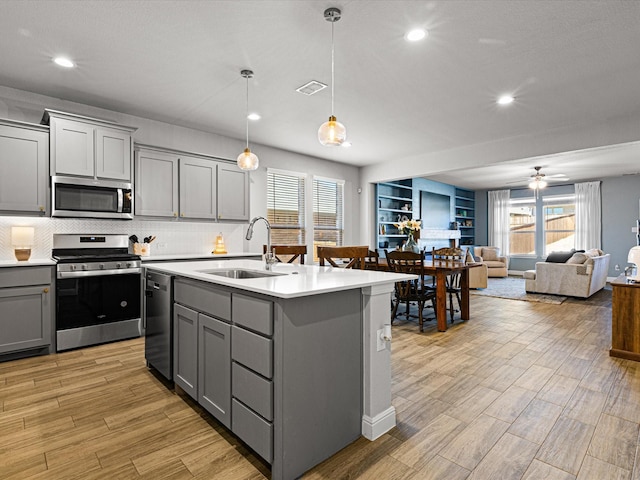 kitchen with appliances with stainless steel finishes, gray cabinets, light countertops, and a sink