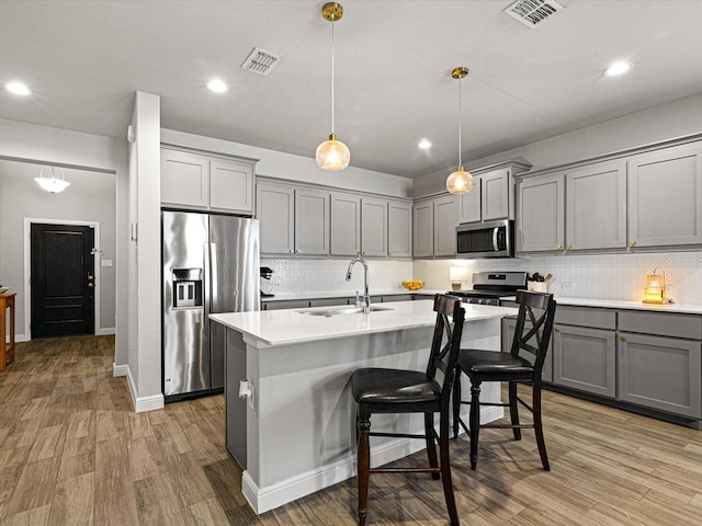 kitchen featuring stainless steel appliances, gray cabinets, visible vents, and a sink