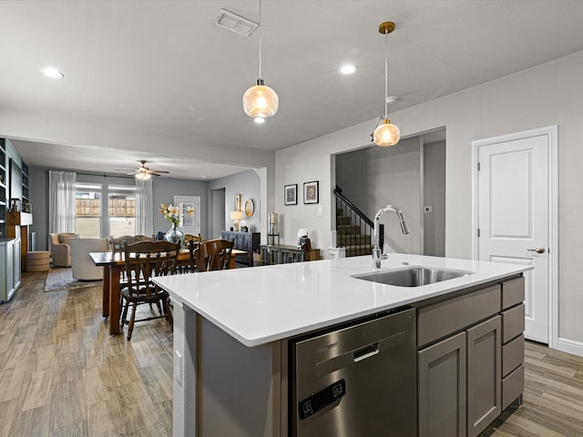 kitchen featuring open floor plan, light countertops, a sink, dishwasher, and gray cabinetry