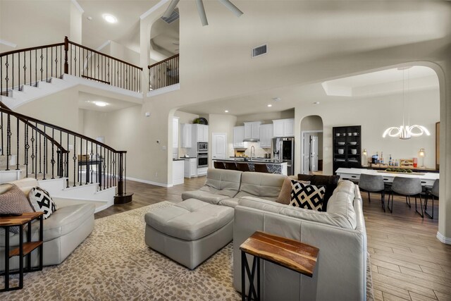 2822 Palmerston Dr, Midlothian, TX 76065 - living area featuring arched walkways, a chandelier, stairway, light wood-style flooring, and a towering ceiling