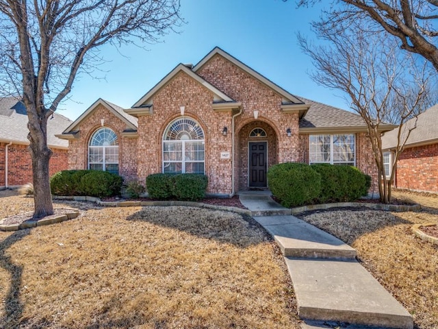 single story home featuring brick siding and roof with shingles