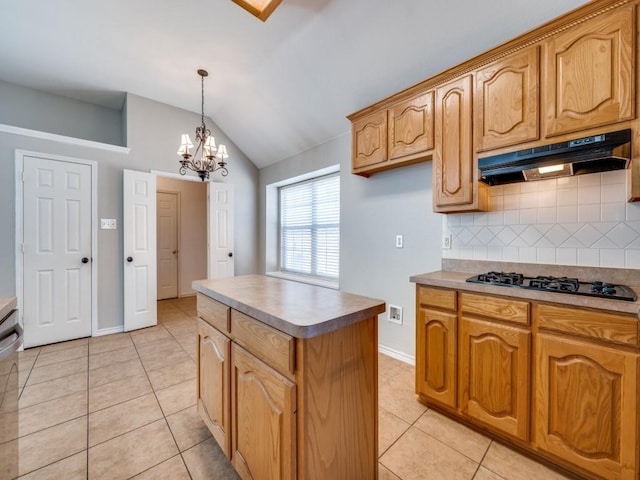 kitchen with light tile patterned floors, black gas stovetop, under cabinet range hood, vaulted ceiling, and a center island