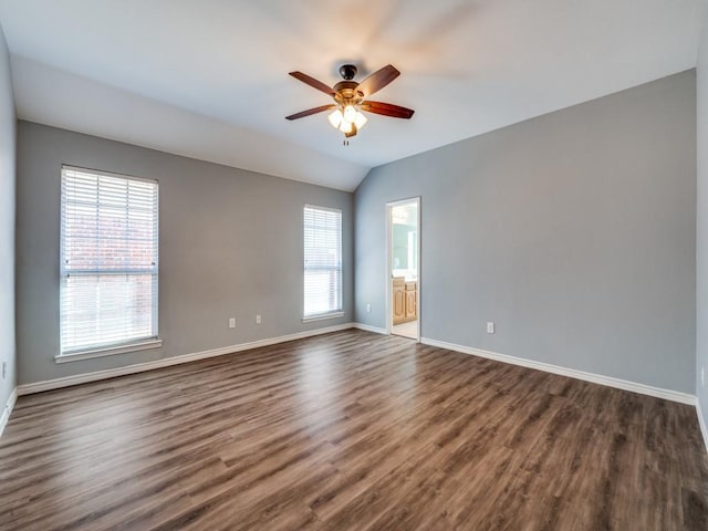 empty room with lofted ceiling, dark wood-style floors, ceiling fan, and baseboards