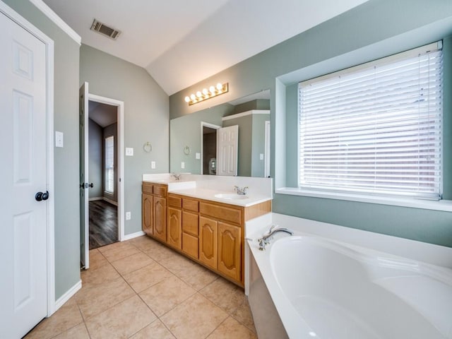 bathroom featuring a garden tub, visible vents, vaulted ceiling, a sink, and tile patterned floors