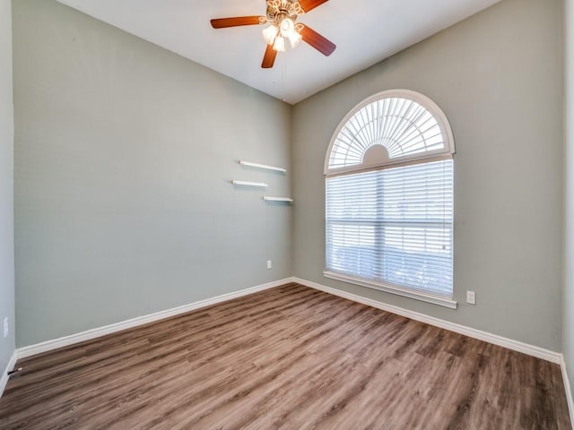 empty room featuring wood finished floors, a ceiling fan, and baseboards