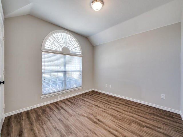 spare room with lofted ceiling, baseboards, and wood finished floors