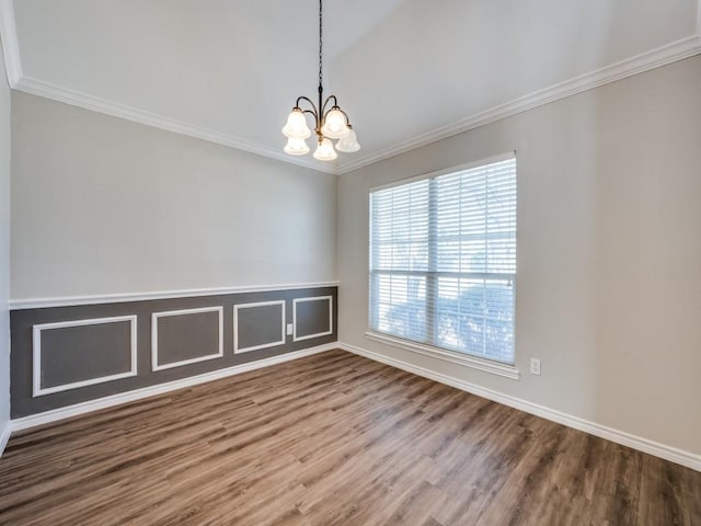 empty room featuring crown molding, a notable chandelier, and wood finished floors