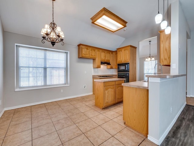 kitchen with a chandelier, under cabinet range hood, vaulted ceiling, hanging light fixtures, and black appliances