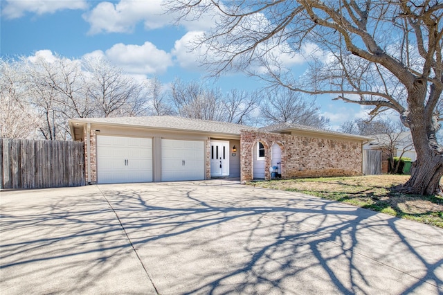 ranch-style home with an attached garage, fence, concrete driveway, and brick siding