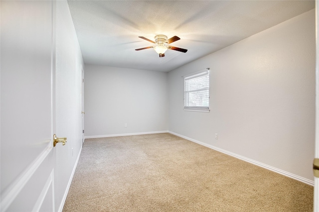 spare room featuring baseboards, a textured ceiling, a ceiling fan, and light colored carpet