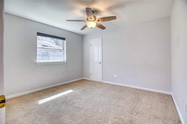 carpeted empty room with ceiling fan and baseboards