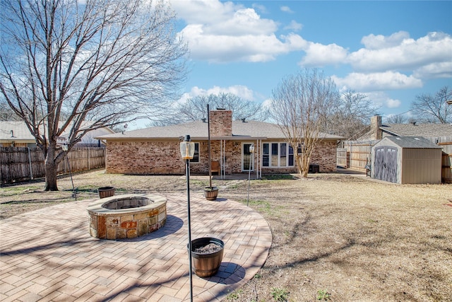 back of house with an outbuilding, a patio, a fire pit, fence, and a storage unit