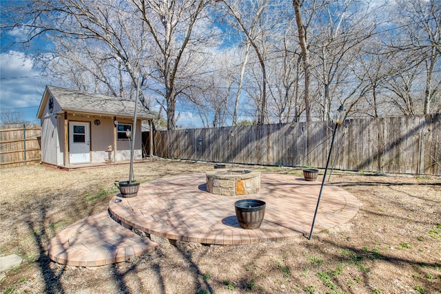 view of yard with a fenced backyard, a fire pit, a patio, and an outbuilding