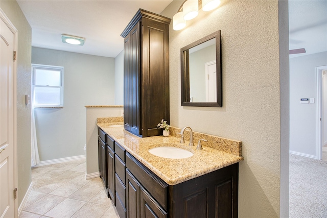 bathroom featuring double vanity, tile patterned floors, a sink, and baseboards