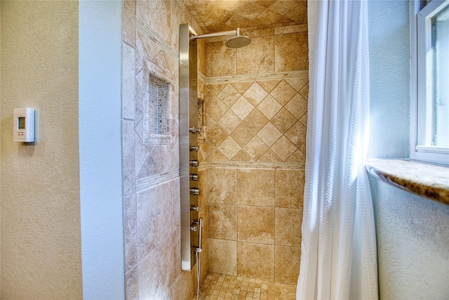 full bathroom with a tile shower and a textured wall