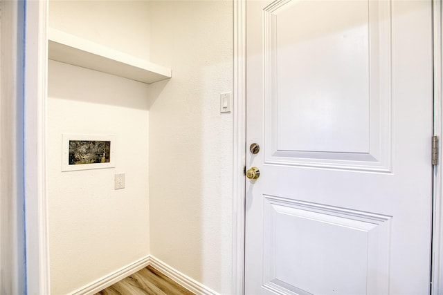 laundry room featuring a textured wall, hookup for a washing machine, laundry area, wood finished floors, and baseboards