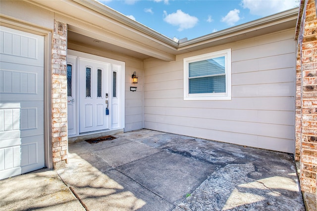 doorway to property with a garage and brick siding