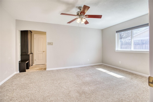 empty room featuring light carpet, baseboards, and a ceiling fan