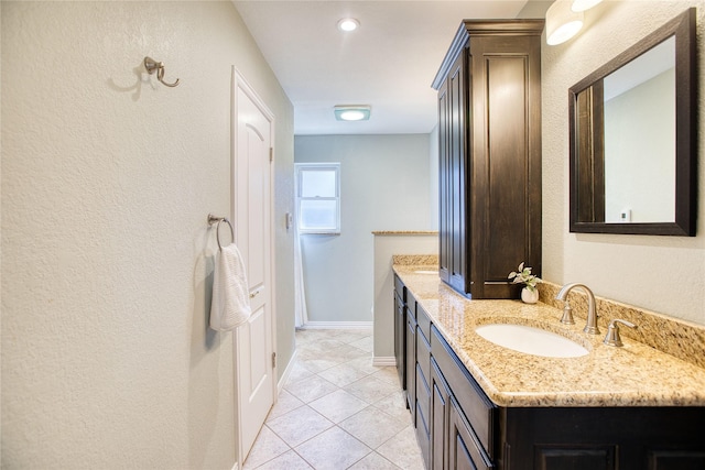 bathroom with a textured wall, tile patterned flooring, baseboards, and vanity