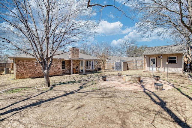 back of house with an outdoor fire pit, fence, a chimney, and a patio