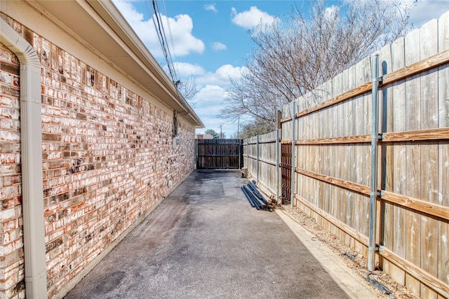 view of side of property with a patio area, brick siding, and fence