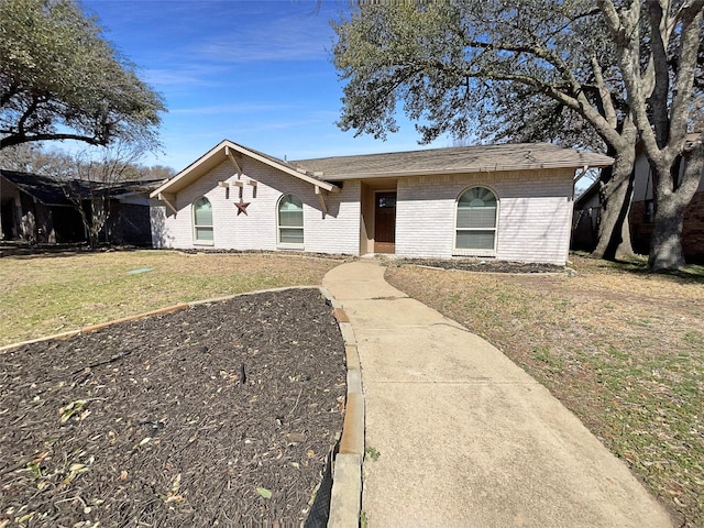 view of front of property with brick siding, a front yard, and a shingled roof