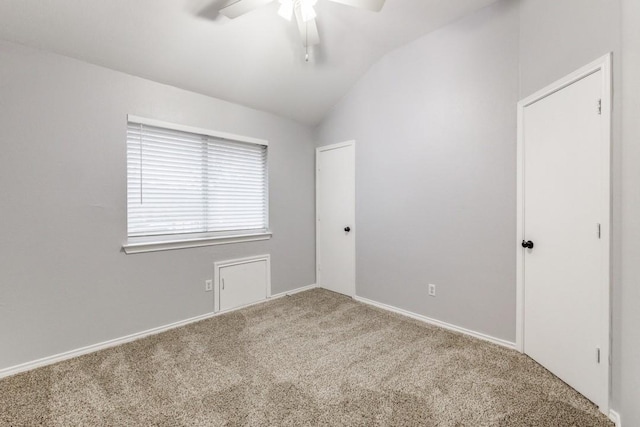 carpeted spare room featuring lofted ceiling and ceiling fan