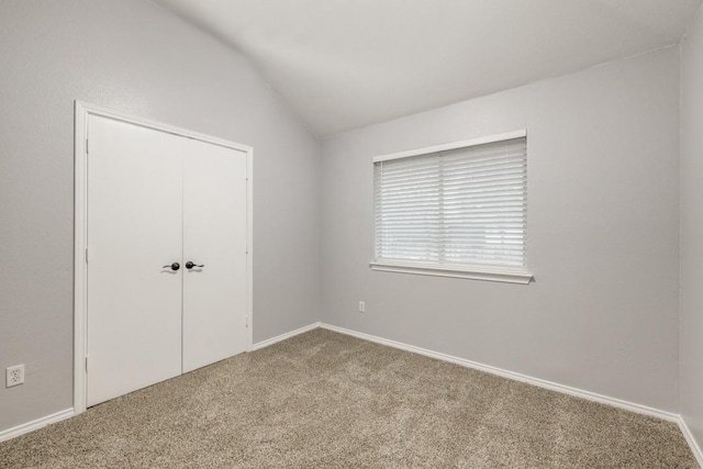 unfurnished bedroom featuring vaulted ceiling, a closet, and carpet flooring