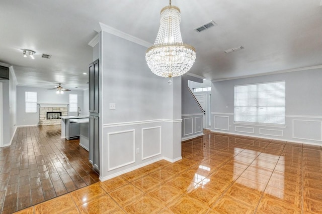 interior space with visible vents, a fireplace, a decorative wall, and ceiling fan with notable chandelier