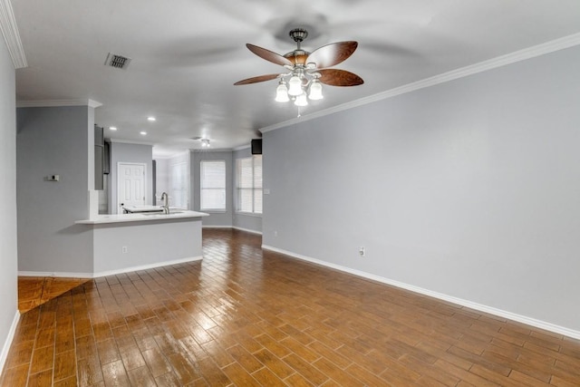 unfurnished living room featuring baseboards, a ceiling fan, ornamental molding, wood finished floors, and a sink