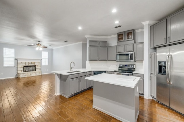 kitchen featuring gray cabinetry, stainless steel appliances, a peninsula, a sink, and visible vents