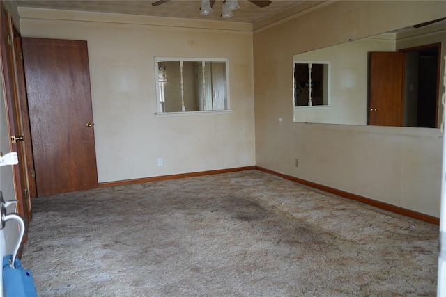 carpeted spare room featuring baseboards, ornamental molding, and a ceiling fan