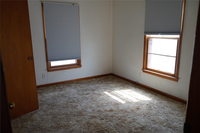 carpeted empty room featuring baseboards and a wealth of natural light