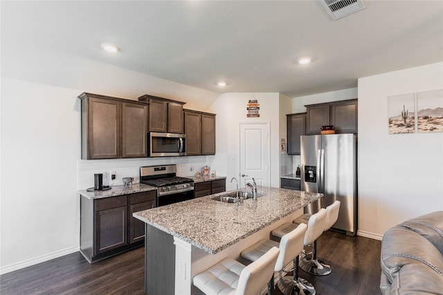 kitchen with visible vents, decorative backsplash, appliances with stainless steel finishes, a sink, and dark brown cabinetry