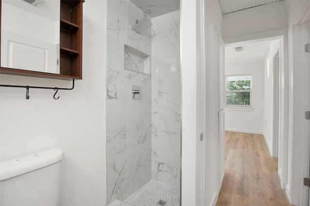 full bath with toilet, wood finished floors, visible vents, baseboards, and a marble finish shower