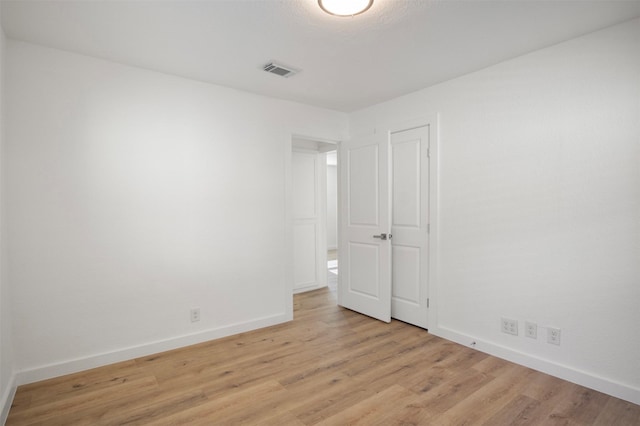 unfurnished room featuring light wood finished floors, visible vents, and baseboards