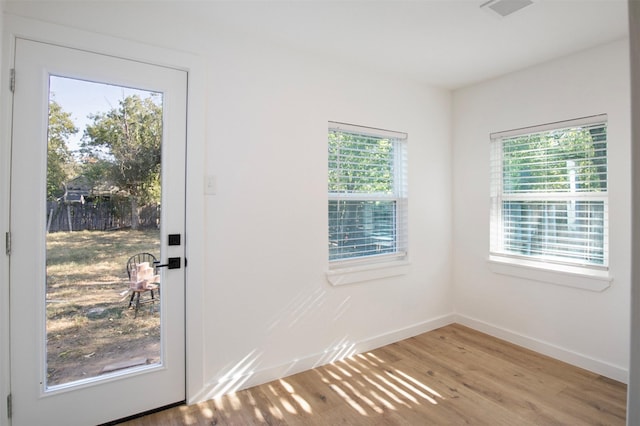 doorway to outside featuring light wood-type flooring, visible vents, and baseboards