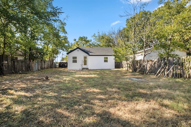 back of house featuring a lawn and fence private yard