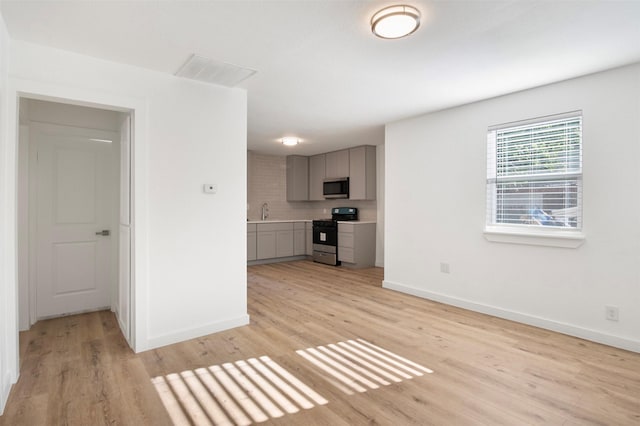 unfurnished living room with light wood-style floors, visible vents, and baseboards