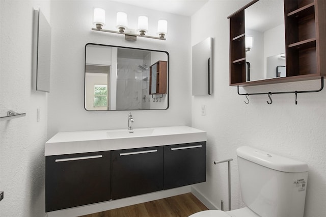 full bathroom with toilet, wood finished floors, vanity, baseboards, and a shower