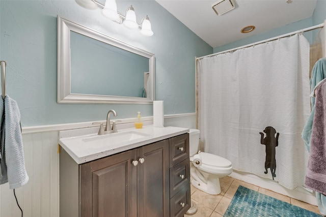 full bath featuring toilet, tile patterned floors, vanity, and wainscoting