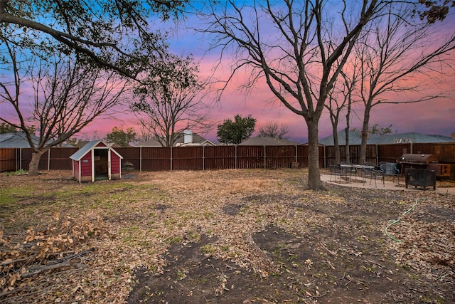 yard at dusk with an outdoor structure and a fenced backyard