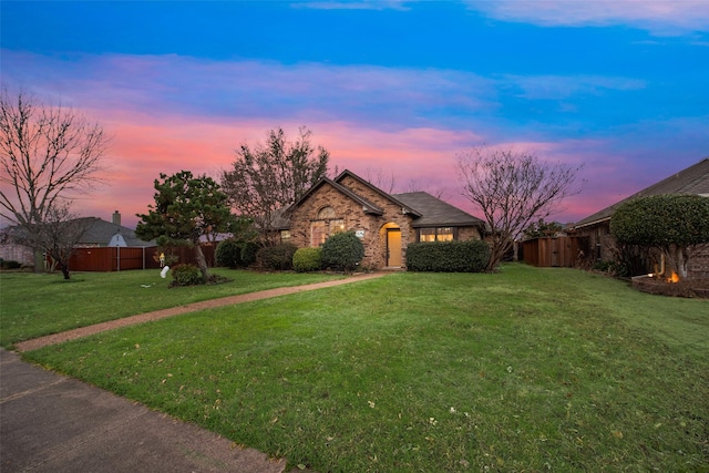 view of front of home featuring brick siding, fence, and a front yard