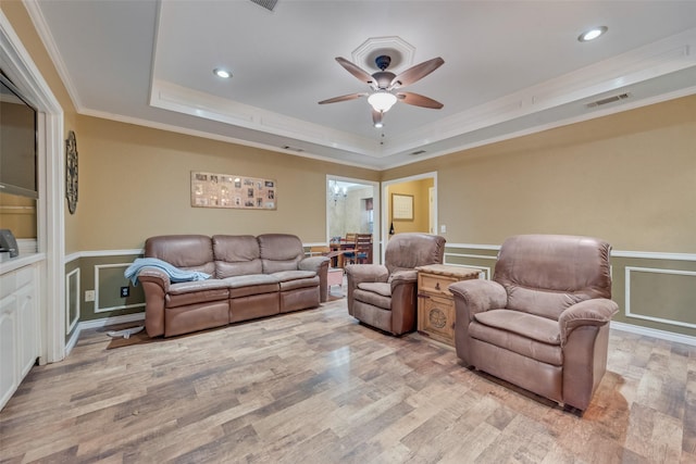 living area featuring light wood-style flooring, crown molding, visible vents, and a tray ceiling