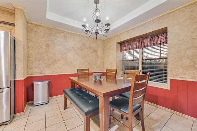 dining area featuring light tile patterned flooring, a tray ceiling, and wainscoting